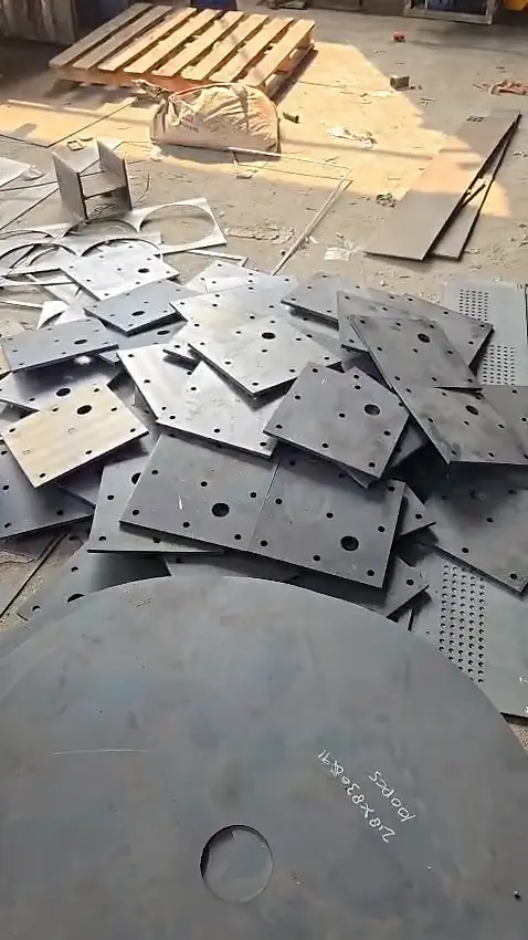 Tumpukan base plate berlubang hasil potong di lantai produksi